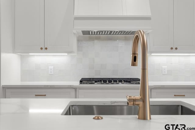 kitchen with backsplash, white cabinetry, and a sink