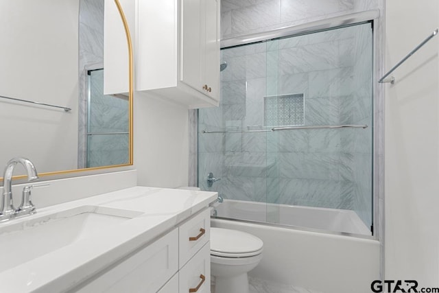 bathroom featuring combined bath / shower with glass door, toilet, and vanity