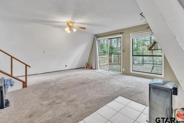 unfurnished living room with ceiling fan, light colored carpet, and a textured ceiling