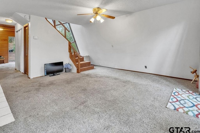 unfurnished living room featuring ceiling fan, carpet floors, and a textured ceiling