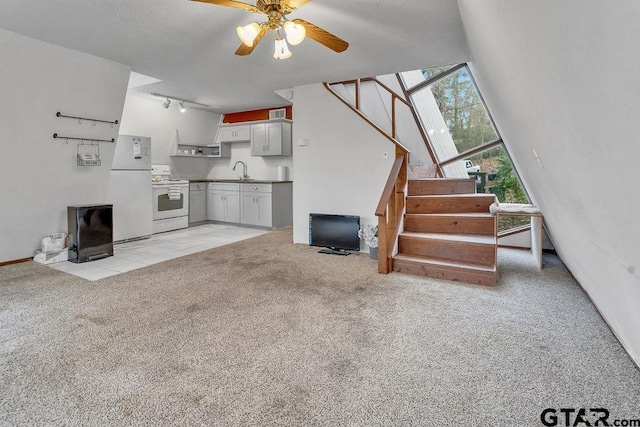 unfurnished living room featuring ceiling fan, light colored carpet, track lighting, and sink