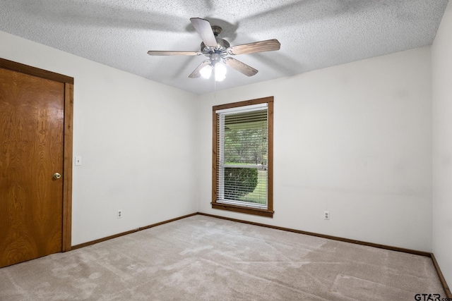 empty room featuring ceiling fan, light colored carpet, and a textured ceiling