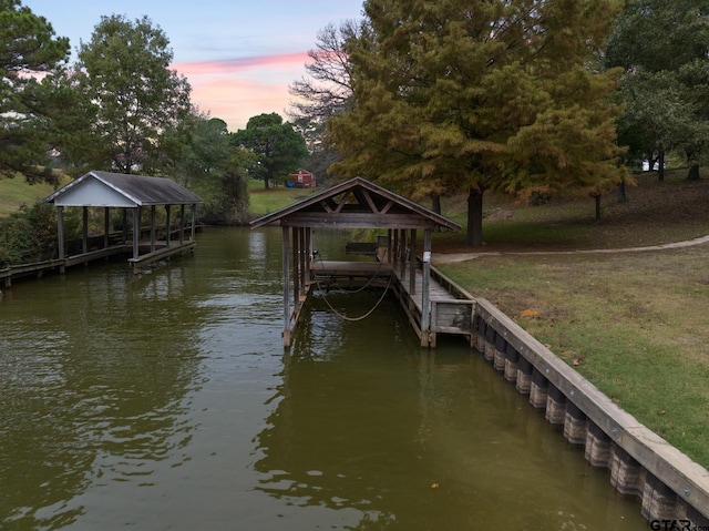 view of dock featuring a gazebo, a lawn, and a water view