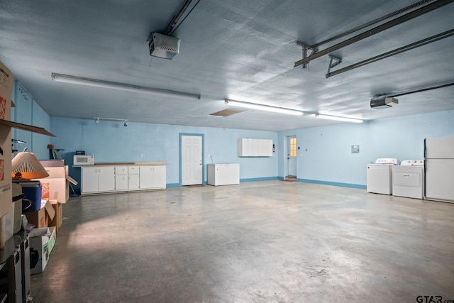 garage with washing machine and clothes dryer, a garage door opener, and white refrigerator