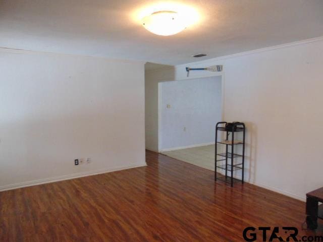 spare room featuring baseboards, crown molding, wood finished floors, and visible vents
