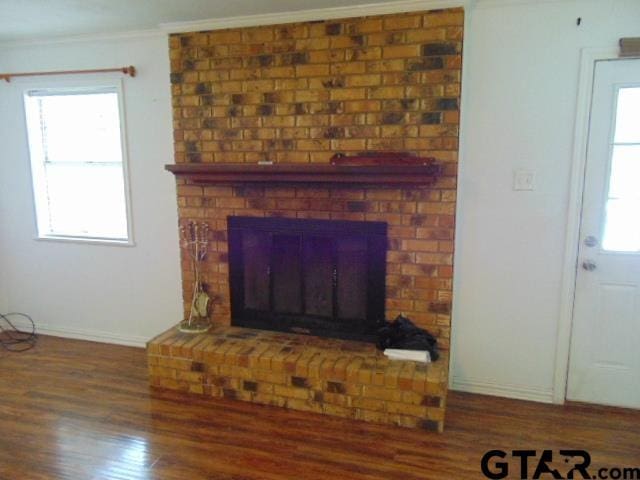 room details with wood finished floors, a brick fireplace, baseboards, and ornamental molding