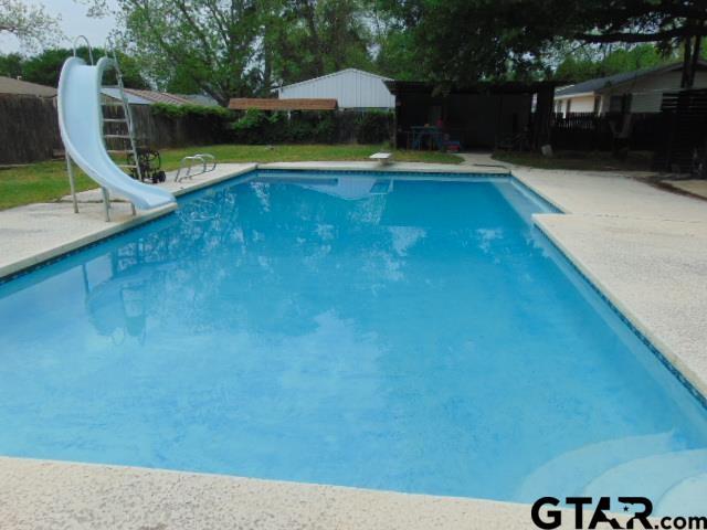 view of swimming pool with a fenced backyard, a fenced in pool, a water slide, and a diving board