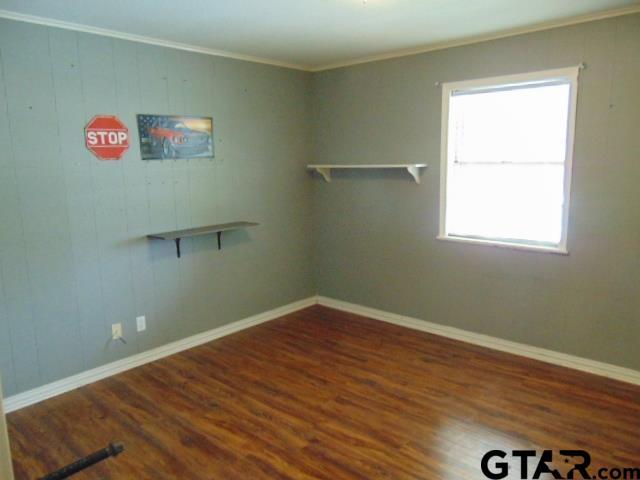 spare room with baseboards, crown molding, and wood finished floors