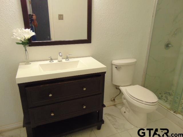 bathroom featuring a marble finish shower, marble finish floor, vanity, and toilet