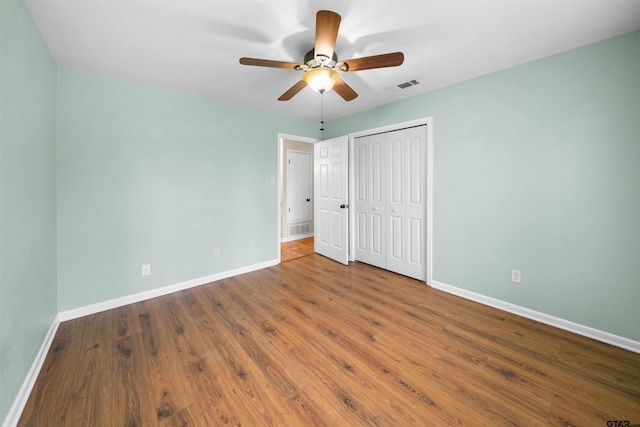 unfurnished bedroom with wood-type flooring, a closet, and ceiling fan