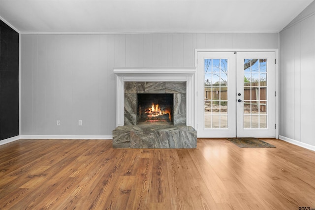 unfurnished living room with a fireplace, wood-type flooring, and french doors