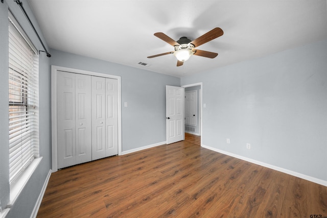 unfurnished bedroom featuring dark wood-type flooring, ceiling fan, and a closet