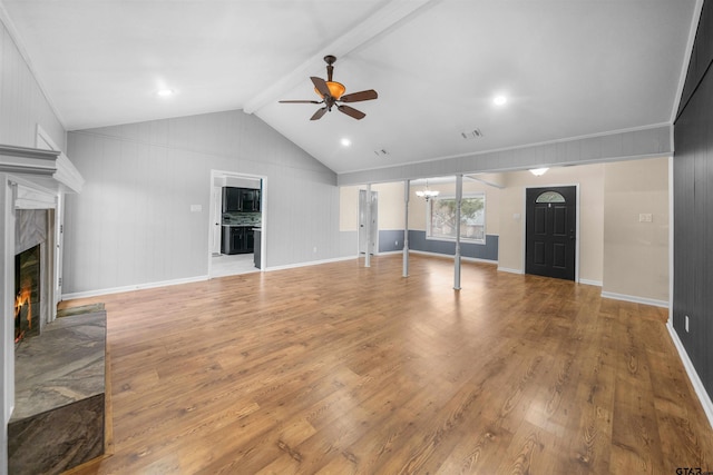 unfurnished living room with lofted ceiling with beams, ceiling fan, a fireplace, and light hardwood / wood-style flooring