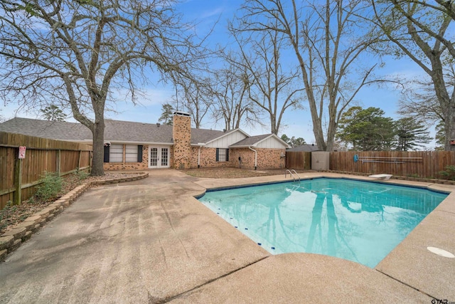 view of swimming pool featuring a patio, a diving board, and french doors