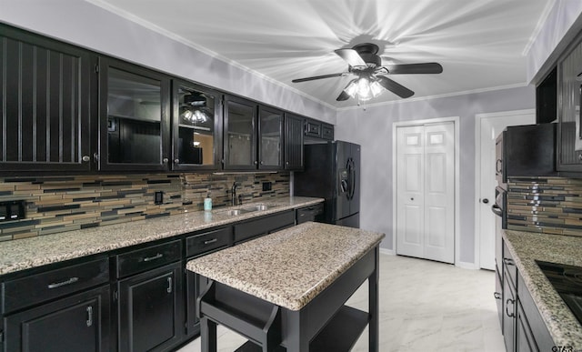 kitchen featuring sink, crown molding, light stone counters, decorative backsplash, and black appliances