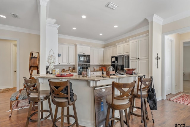 3953 Hanover Pl, Tyler, TX 75701 - kitchen featuring black appliances, a kitchen bar, light wood-type flooring, recessed lighting, and crown molding