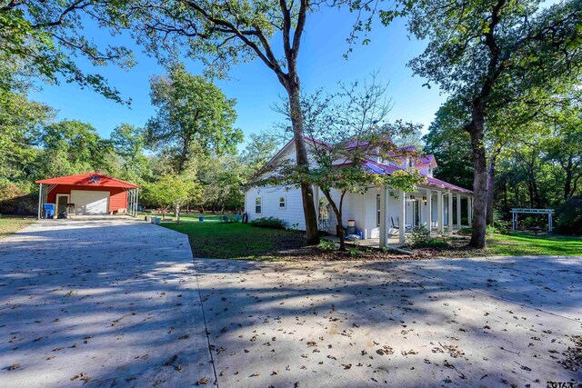 view of front of house with a garage, covered porch, a carport, a front yard, and an outdoor structure