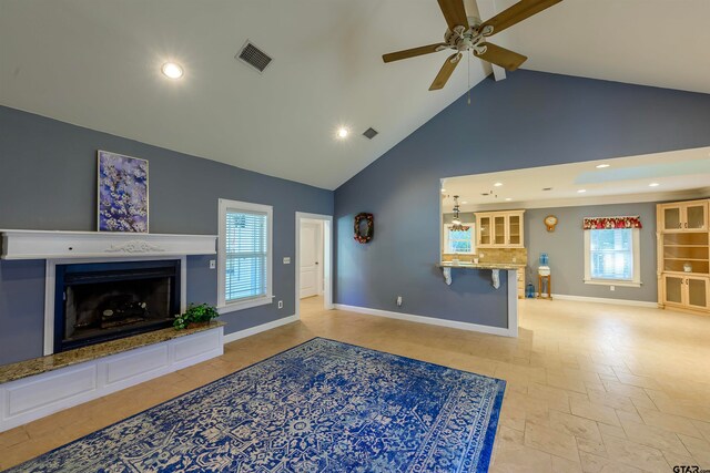 living room with a wealth of natural light, ceiling fan, and high vaulted ceiling