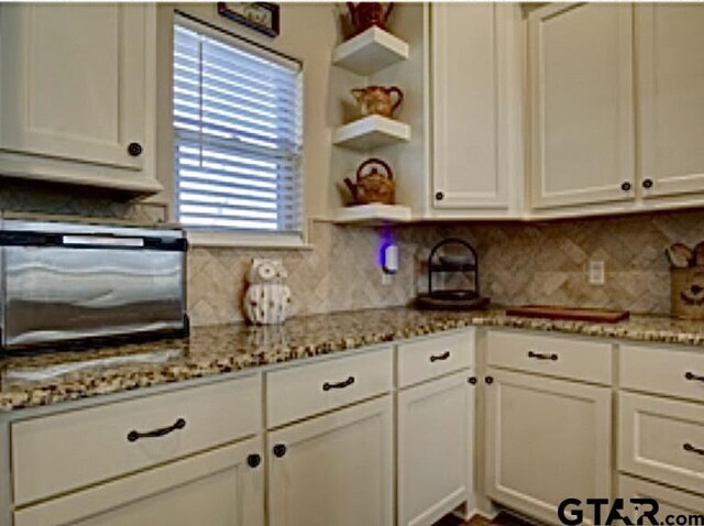 kitchen featuring tasteful backsplash, open shelves, and white cabinetry