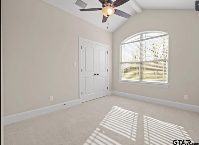 carpeted empty room with visible vents, baseboards, vaulted ceiling with beams, and a ceiling fan