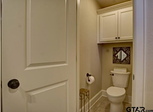 bathroom featuring toilet, baseboards, and tile patterned flooring
