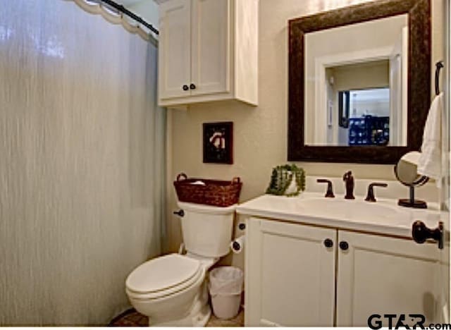 bathroom with toilet, curtained shower, and vanity