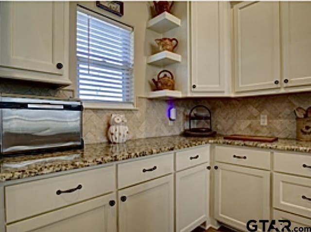 kitchen featuring tasteful backsplash, open shelves, and white cabinetry