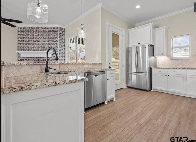 kitchen with tasteful backsplash, white cabinets, a healthy amount of sunlight, a sink, and stainless steel appliances