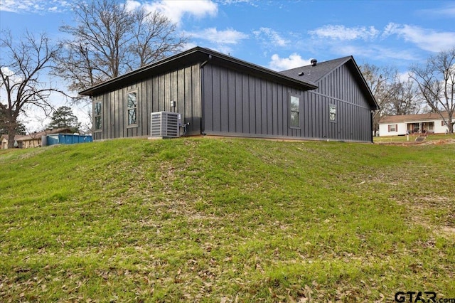 view of side of property with a lawn and central AC