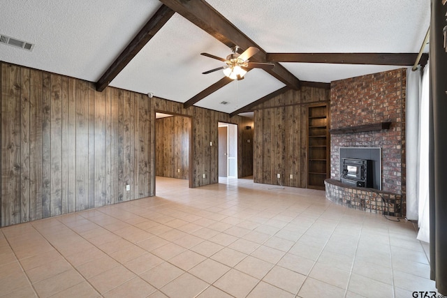 unfurnished living room featuring tile patterned flooring, wooden walls, visible vents, and a textured ceiling