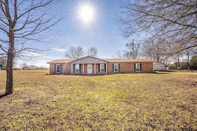 ranch-style home with a front yard, an outbuilding, and brick siding