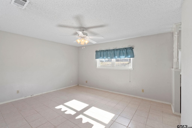 empty room with ceiling fan, light tile patterned floors, and a textured ceiling