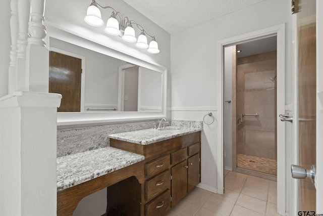 bathroom with a tile shower, tile patterned floors, vanity, and a textured ceiling