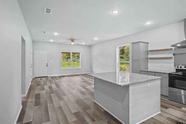 kitchen with a kitchen island, gray cabinetry, backsplash, hardwood / wood-style flooring, and electric range