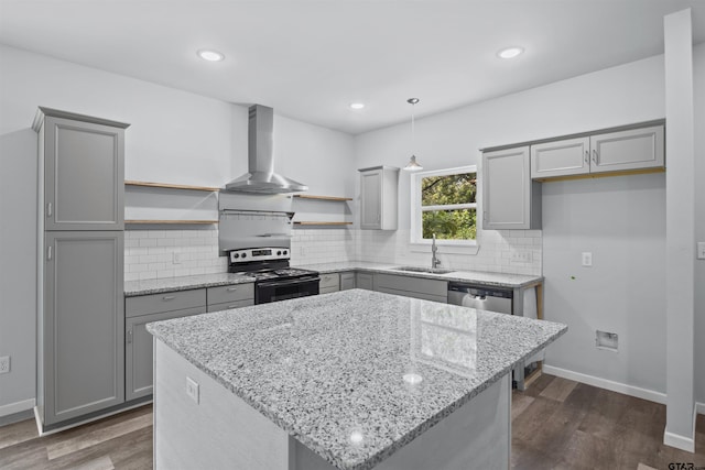 kitchen with sink, appliances with stainless steel finishes, light stone countertops, a kitchen island, and wall chimney exhaust hood