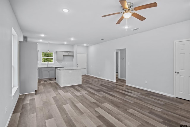 unfurnished living room with hardwood / wood-style flooring, sink, and ceiling fan