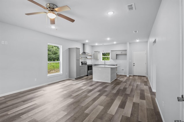 kitchen with wall chimney range hood, hardwood / wood-style flooring, gray cabinetry, a center island, and stainless steel range with electric cooktop