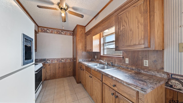 kitchen featuring white electric range oven, sink, a textured ceiling, ornamental molding, and wooden walls