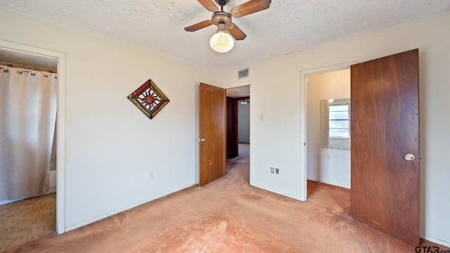 unfurnished bedroom featuring ceiling fan, light carpet, and a textured ceiling