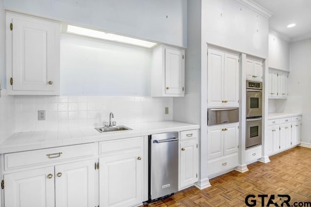 kitchen featuring stainless steel double oven, white cabinets, a warming drawer, and a sink