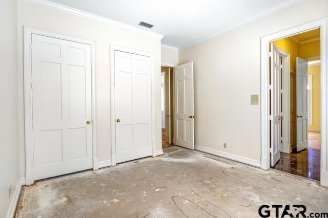 unfurnished bedroom with ornamental molding, visible vents, baseboards, and two closets