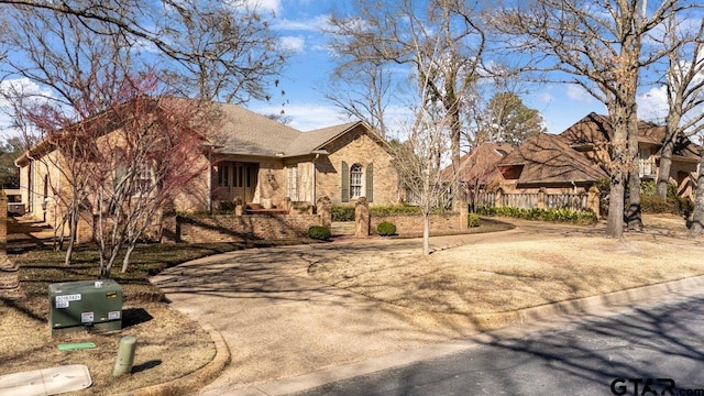 view of front facade with roof with shingles, fence, and brick siding