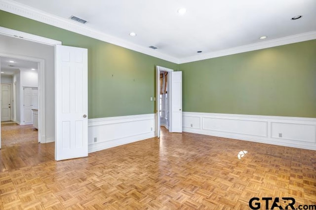 empty room featuring recessed lighting, a wainscoted wall, visible vents, and crown molding