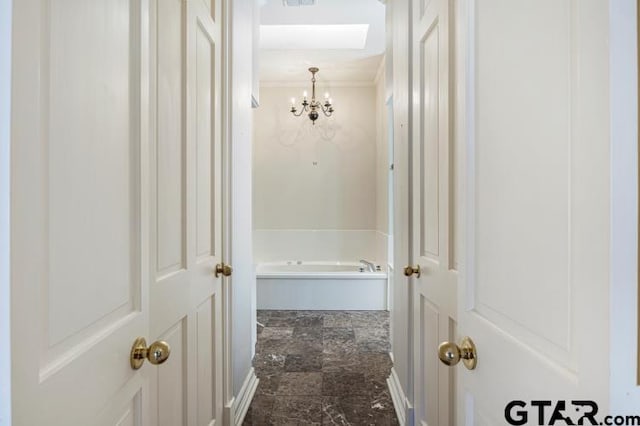 hallway with stone finish floor, visible vents, crown molding, and an inviting chandelier