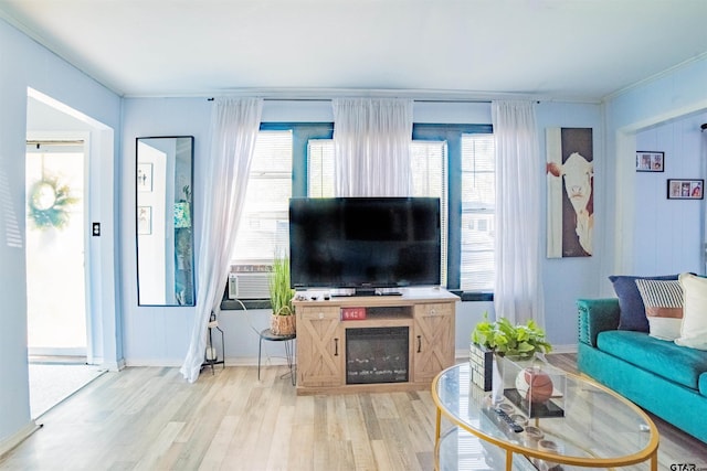 living room featuring light wood-type flooring, baseboards, and a healthy amount of sunlight