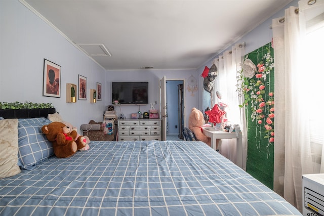 bedroom with attic access, visible vents, and crown molding