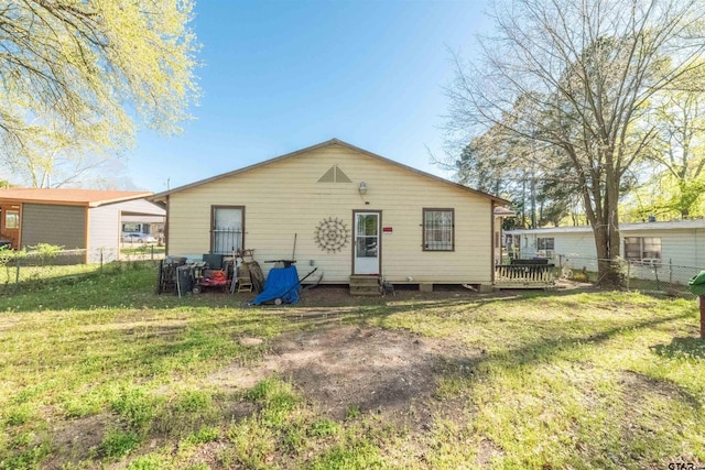 rear view of house with a yard, entry steps, and fence