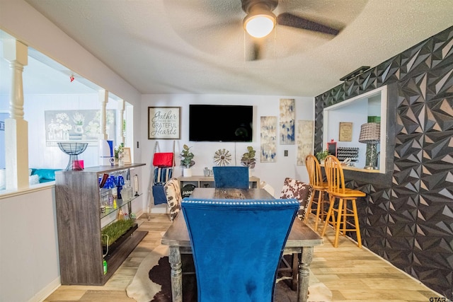 interior space with baseboards, a ceiling fan, wood finished floors, and a textured ceiling