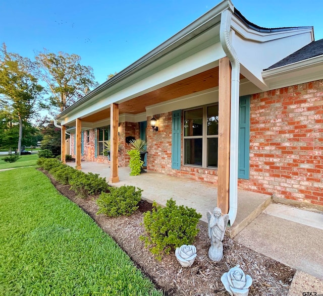 view of exterior entry with a porch and a yard