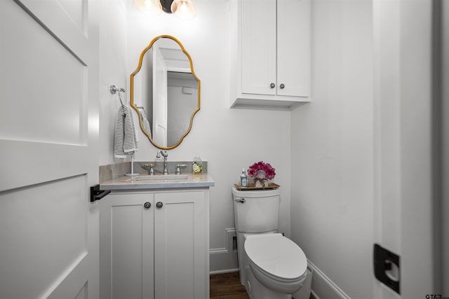 half bathroom featuring vanity, toilet, and baseboards